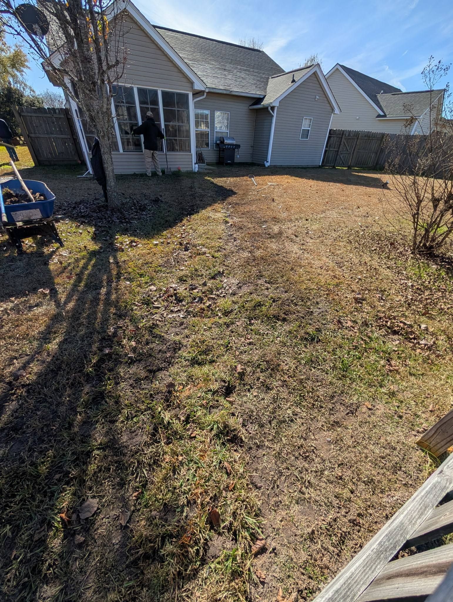 Small suburban front yard with dry grass leading to a white house and garage under bright sunlight