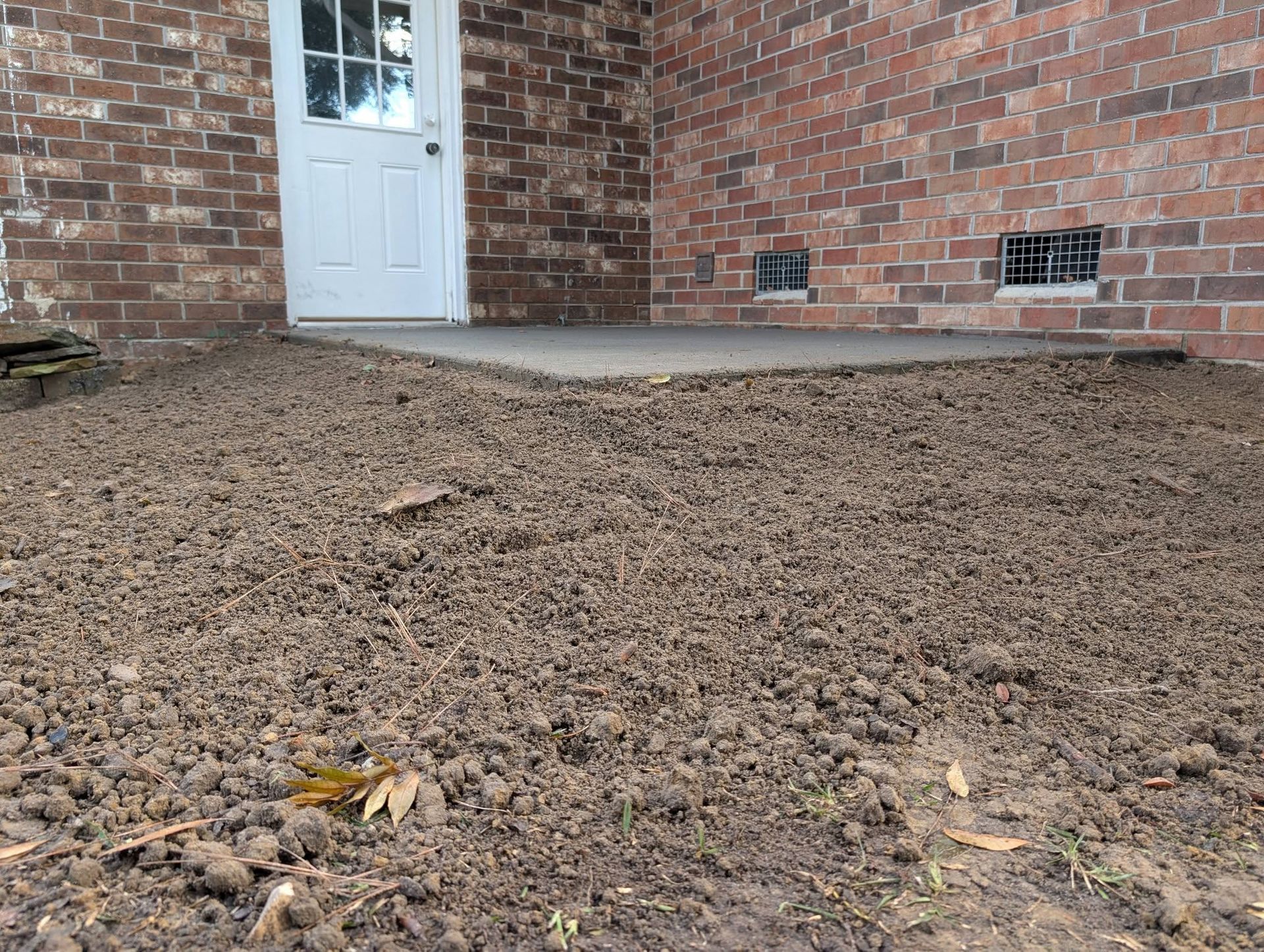 Brick house exterior with white door and a gravel-covered yard in front