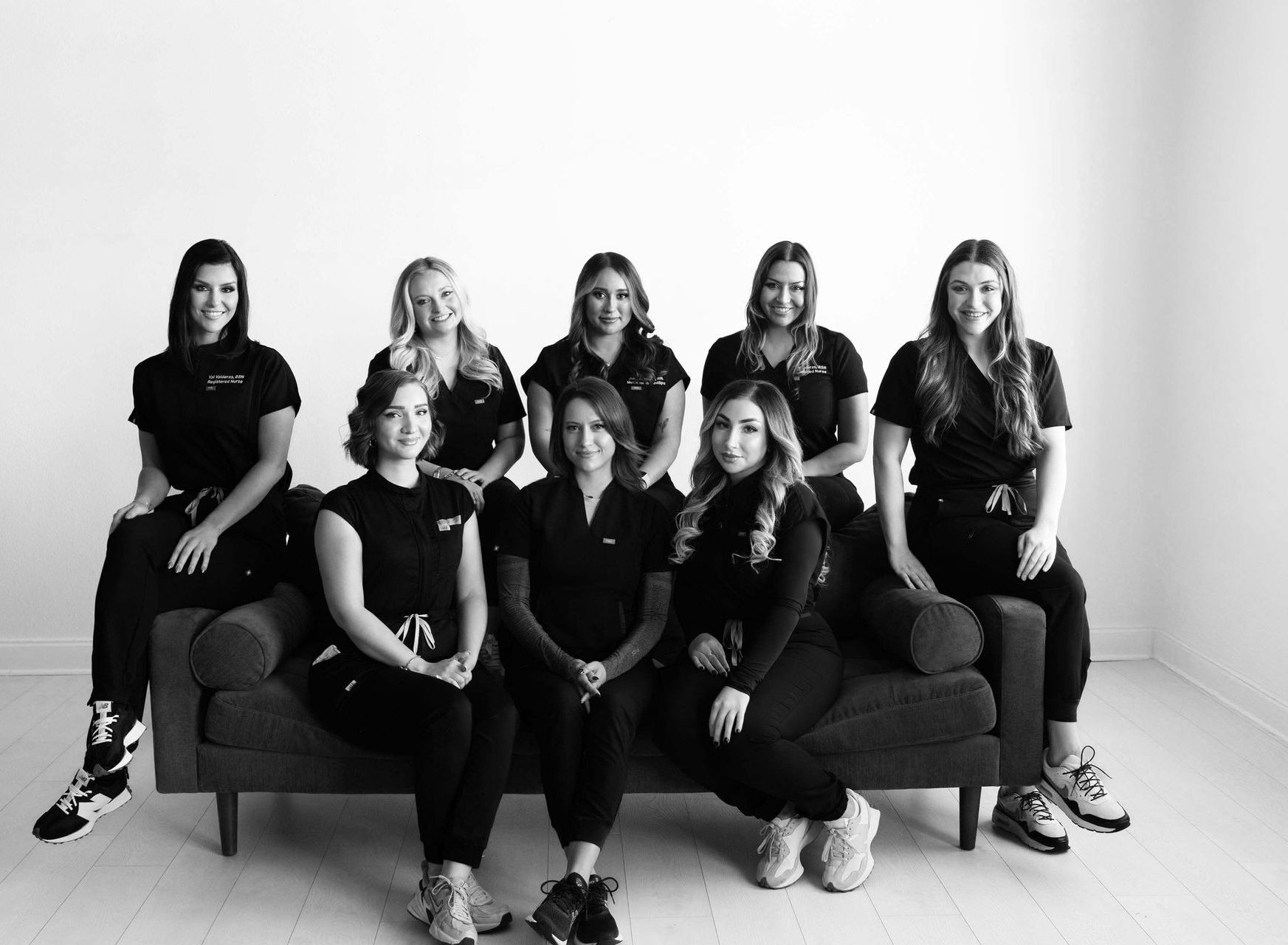 Eight people seated and standing around a couch in a bright studio, posing for a group portrait.