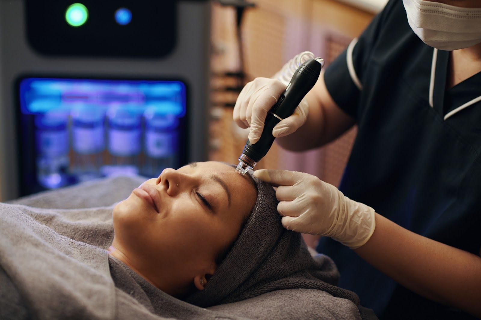 Aesthetic facial treatment with a handheld device on a client lying on a spa bed