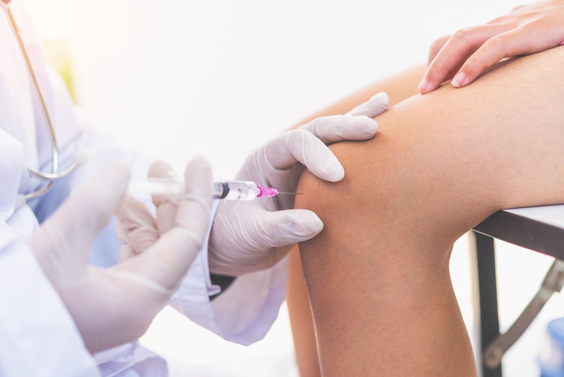 Nurse injecting vaccine into a patient’s bent knee in a clinical setting