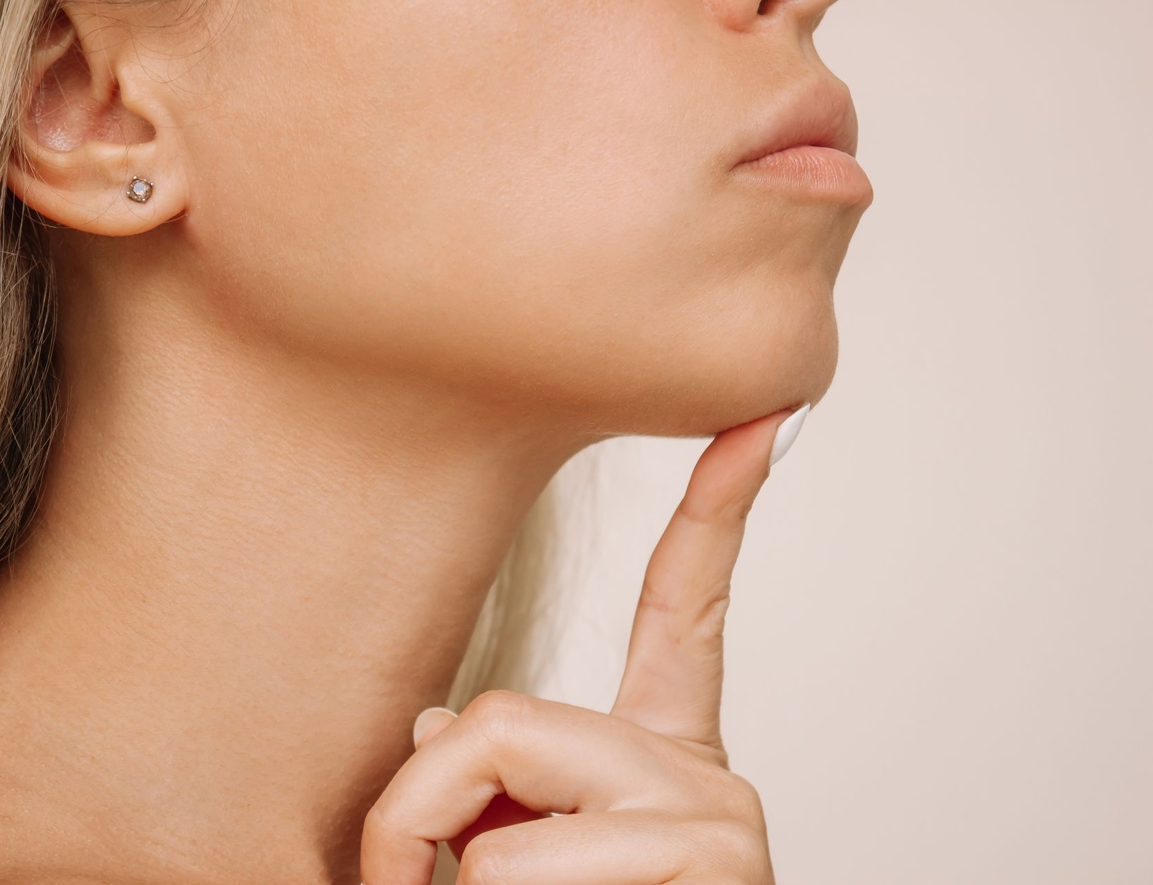 Person touching chin with finger, showing a side profile against a plain background