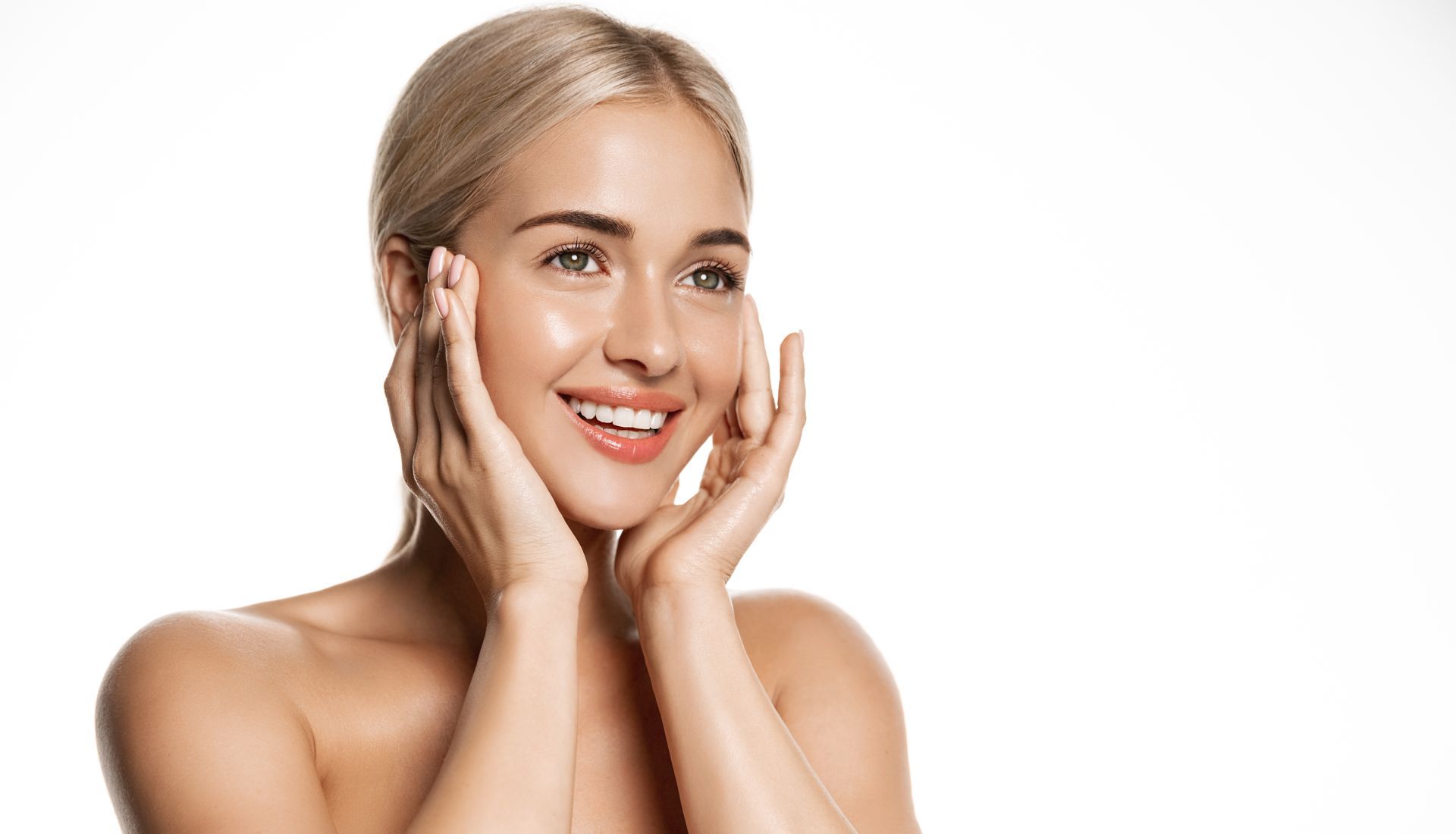 Smiling person with blonde hair holding cheeks against a white background