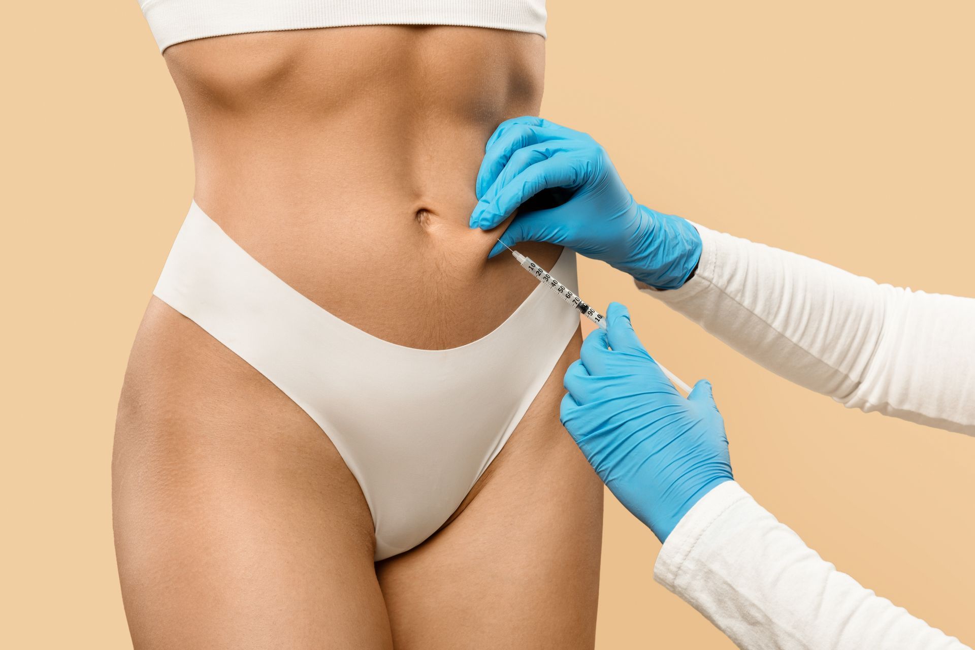 Close-up of a person’s waist as gloved hands inject the abdomen with a syringe.