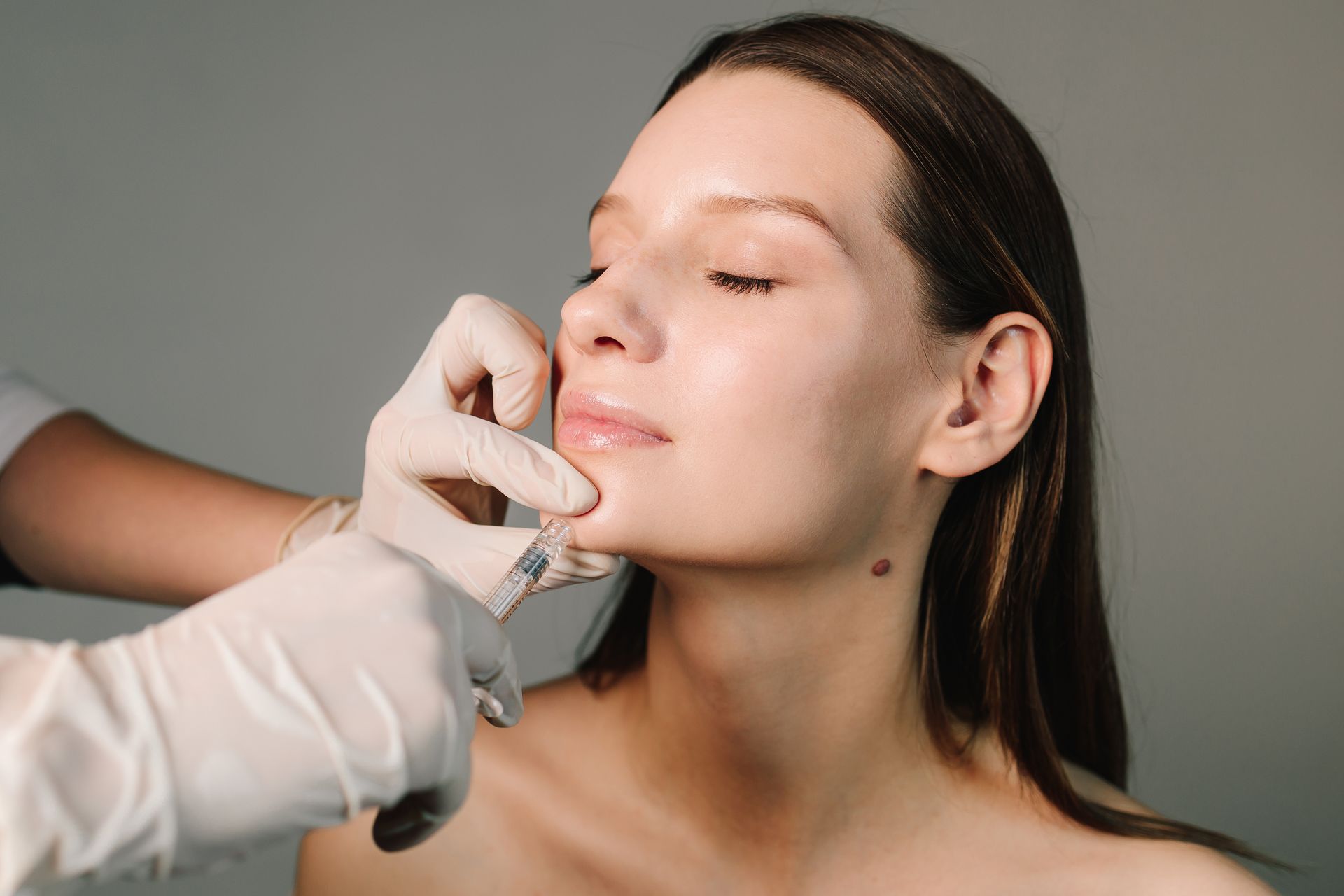 Cosmetic procedure on a woman's face using a handheld device in a clinic setting