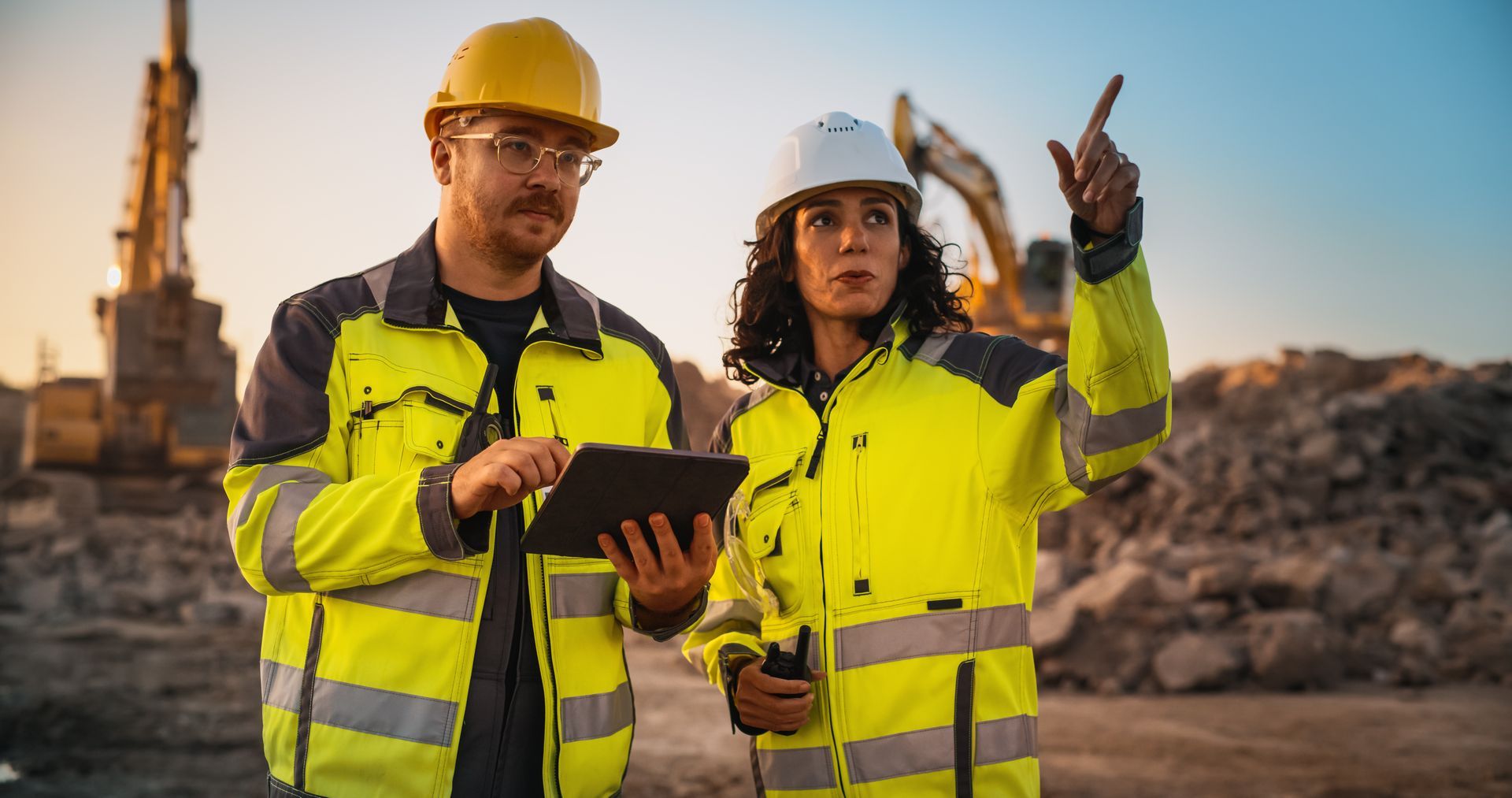 Two excavation contractors are on a construction site, inspecting the work.