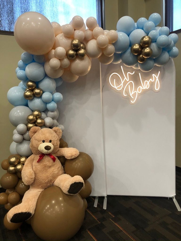 A bride to be neon sign is surrounded by balloons in front of a brick wall.