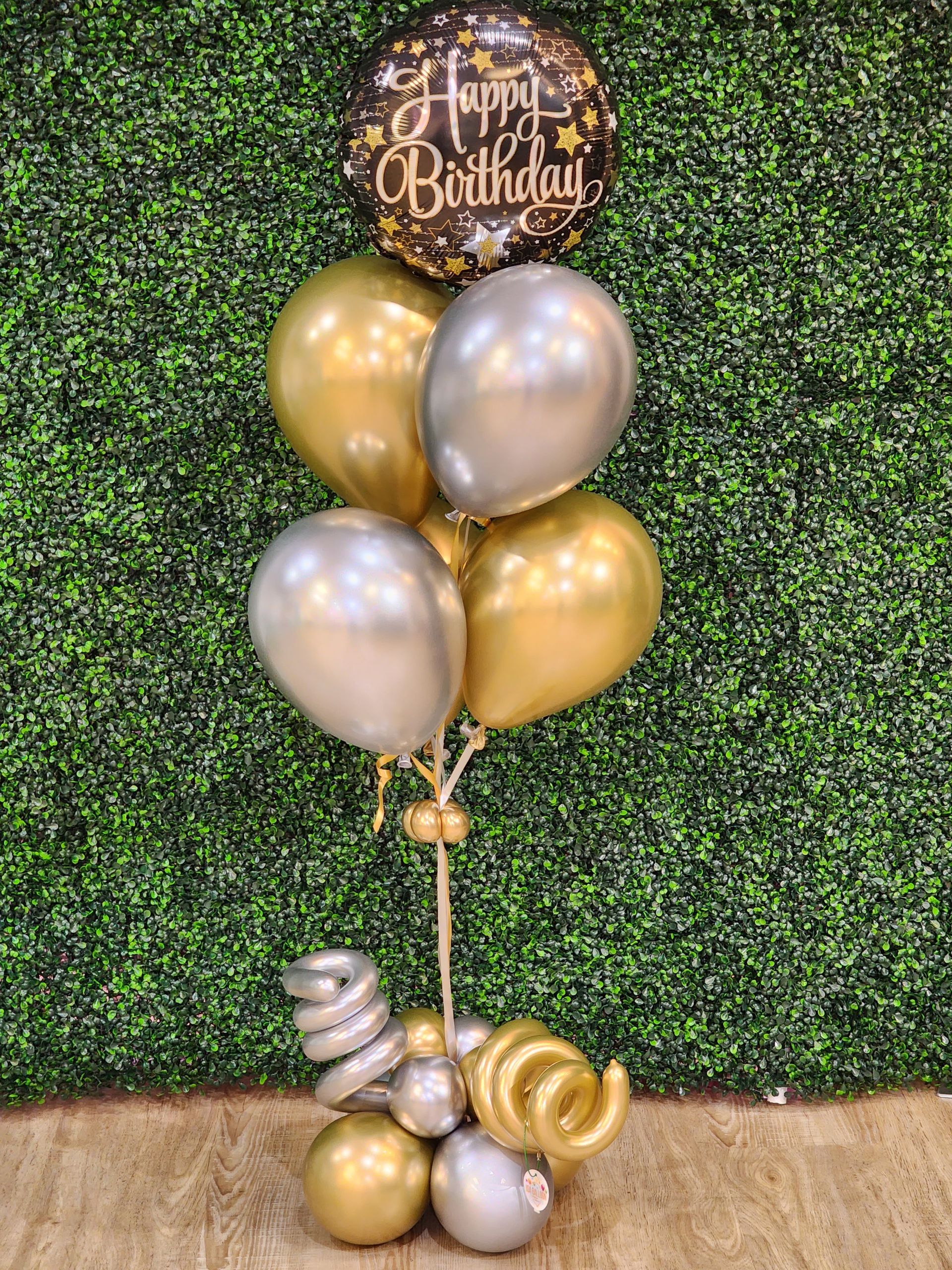 A bunch of gold and silver balloons are sitting on a table.