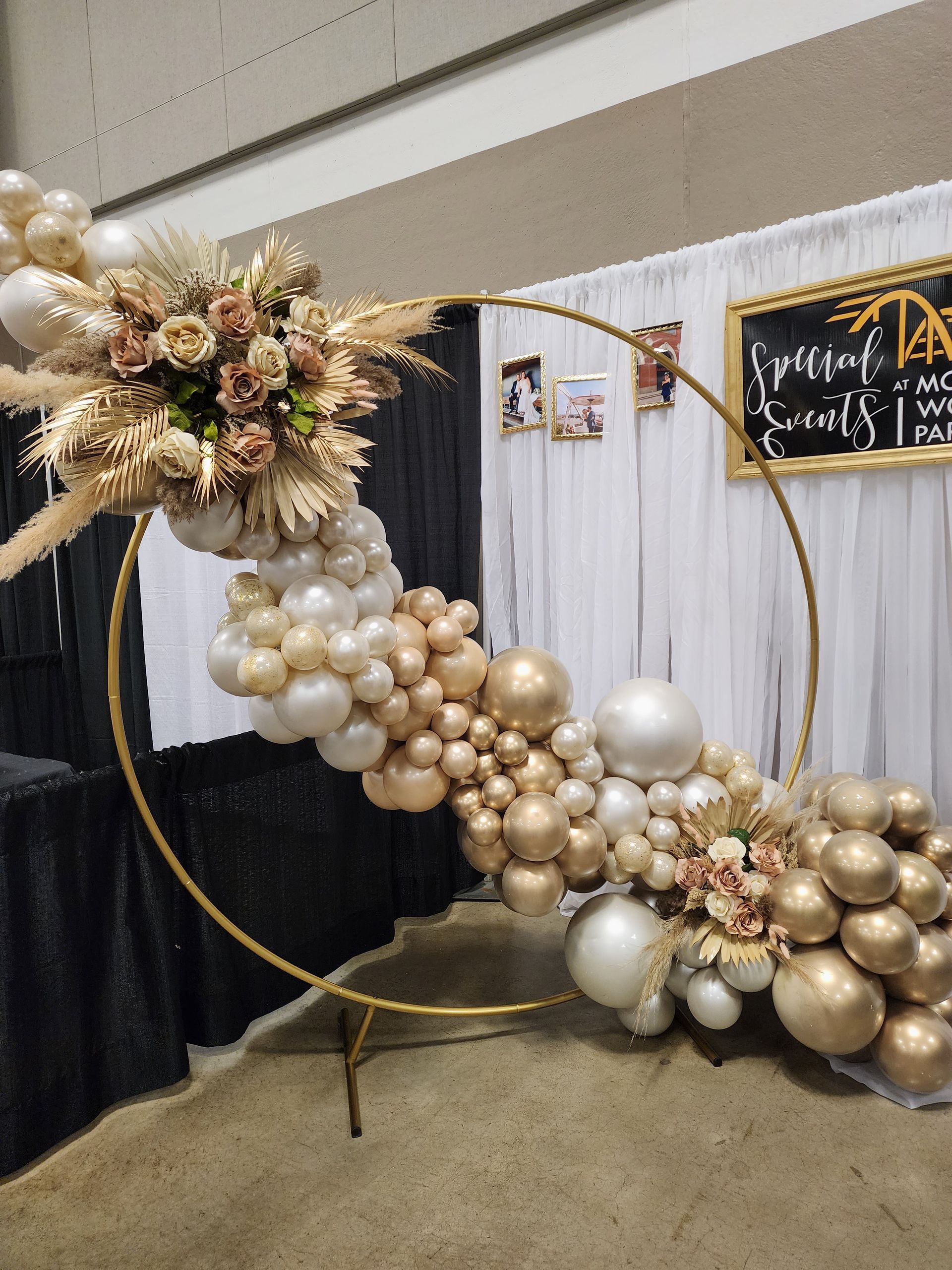 A circle filled with balloons and flowers in a room.