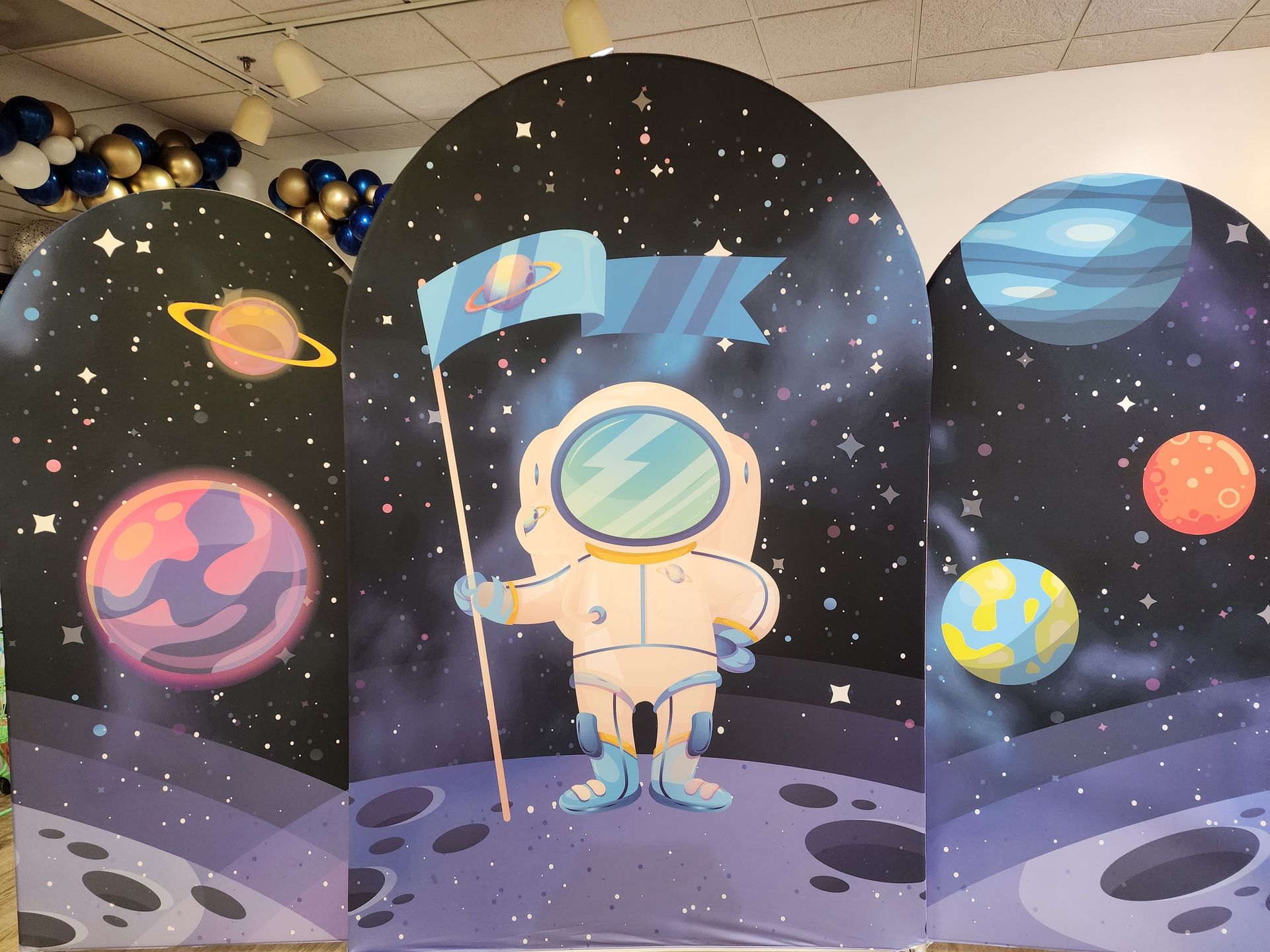 A painting of an astronaut holding a flag with planets in the background.