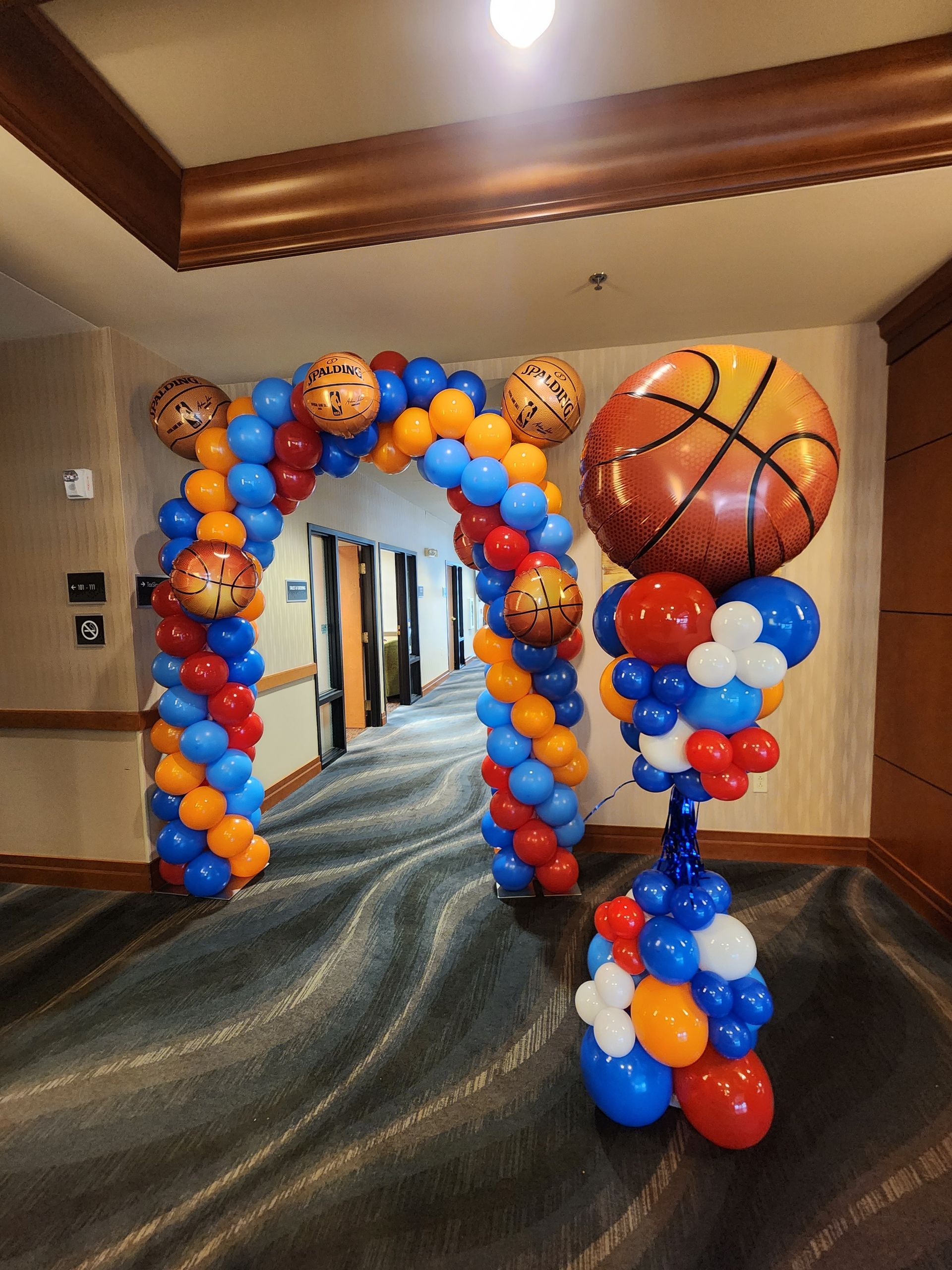 A hallway decorated with balloons and a basketball arch