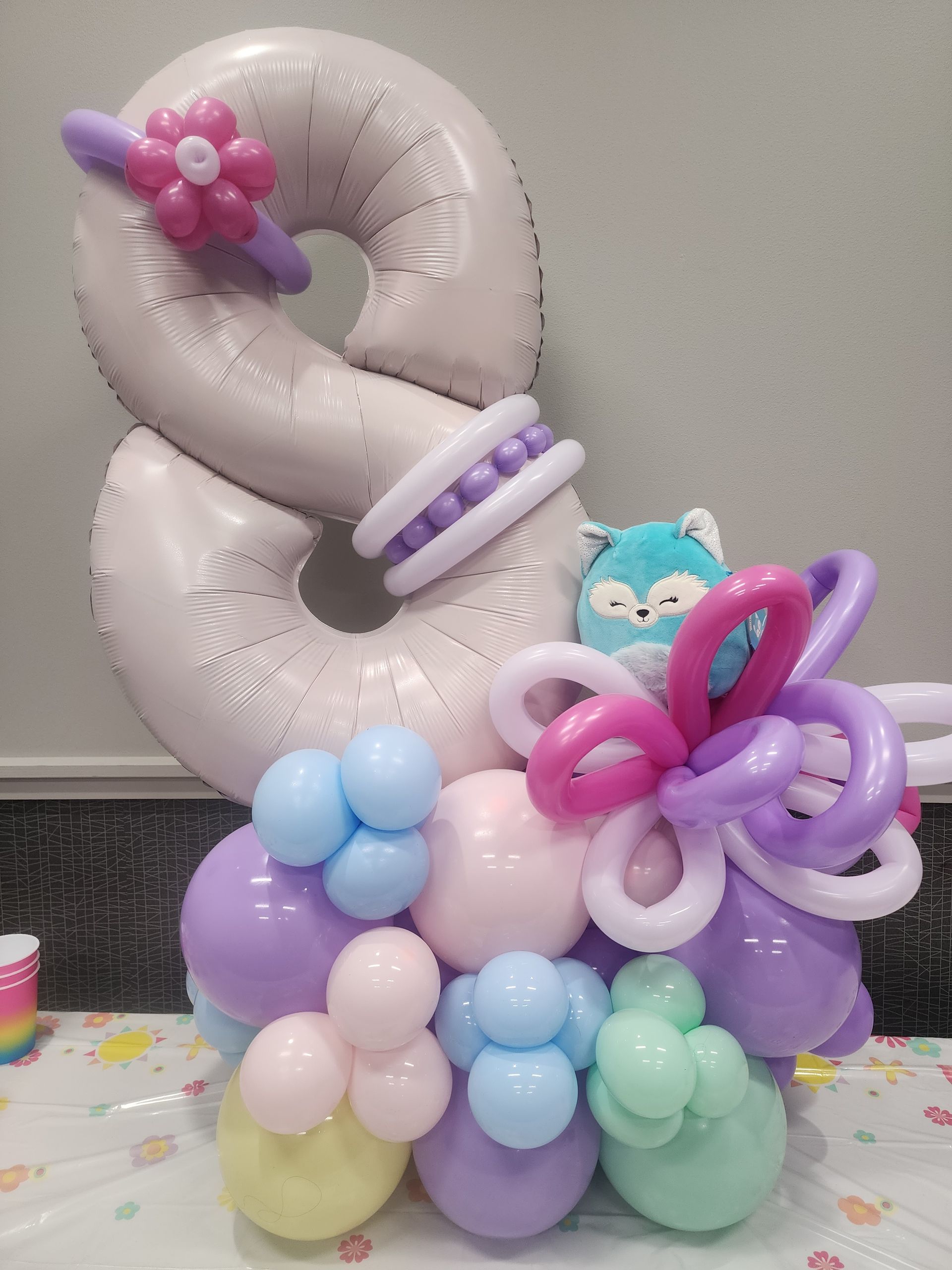 A number 8 balloon is surrounded by balloons on a table.