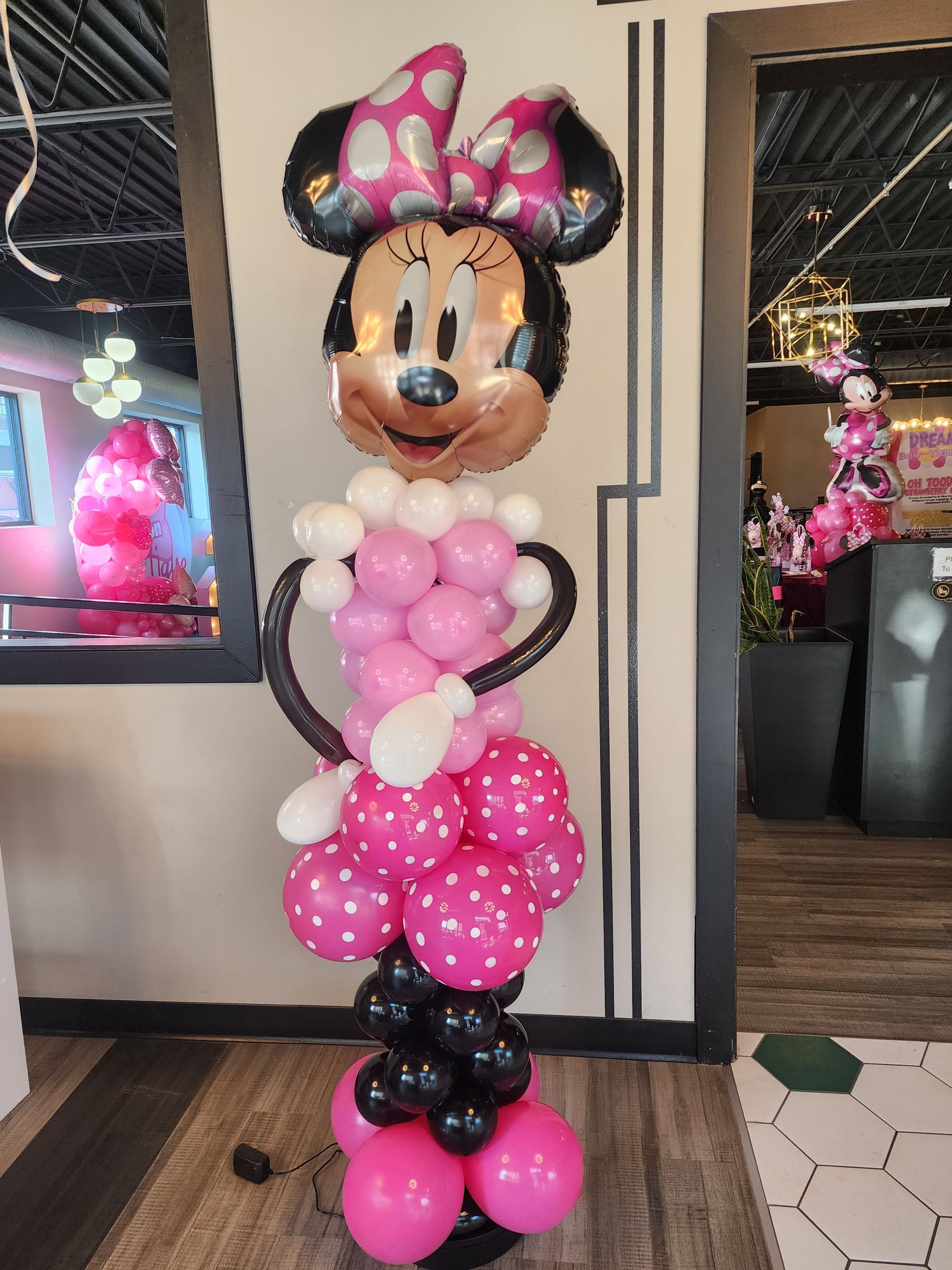 A balloon sculpture of minnie mouse made of pink and black balloons.