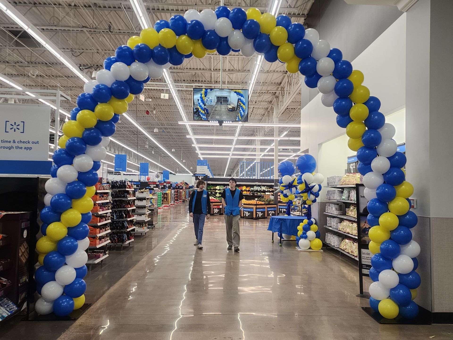 A blue and yellow balloon arch in a grocery store