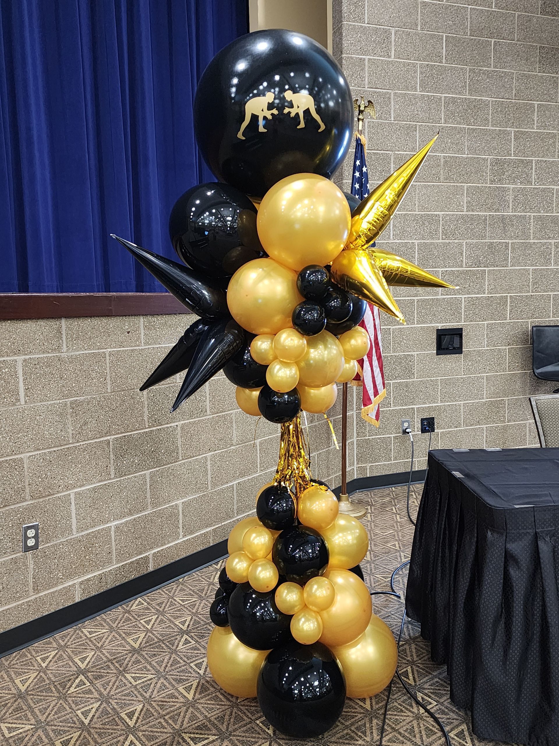 A tower of black and gold balloons in a room.