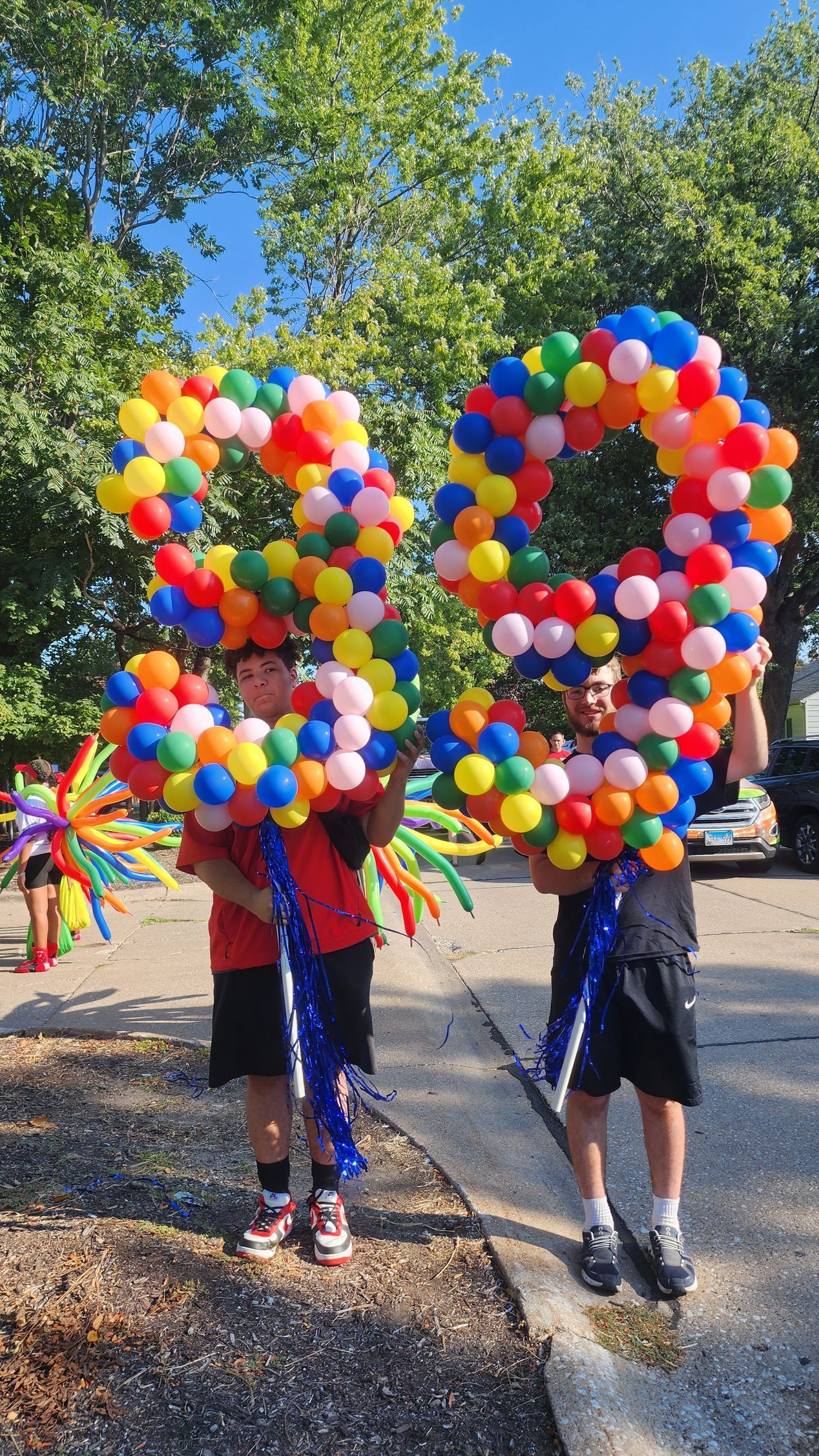Two young boys are holding balloons in the shape of the number 20.