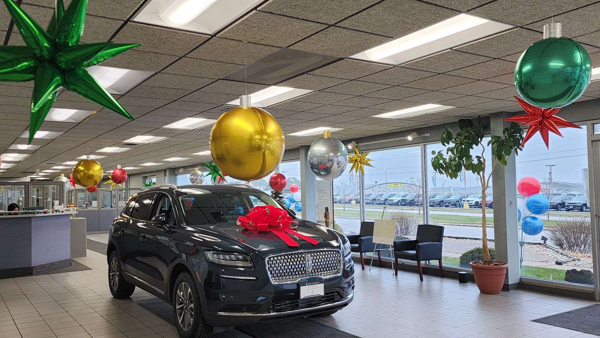 A car is sitting in a showroom decorated for christmas.