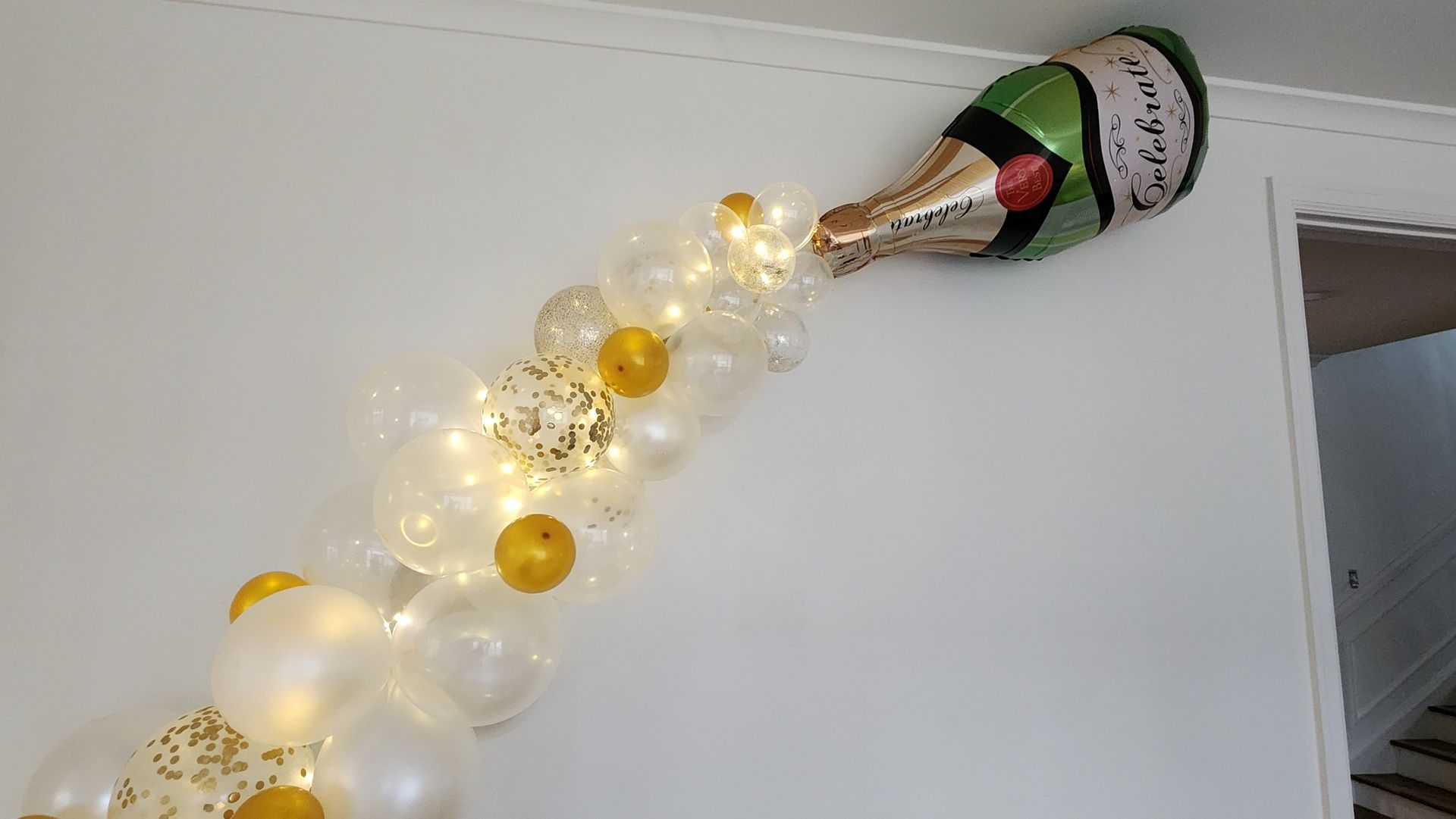 A bottle of champagne is being poured out of a balloon on a wall.