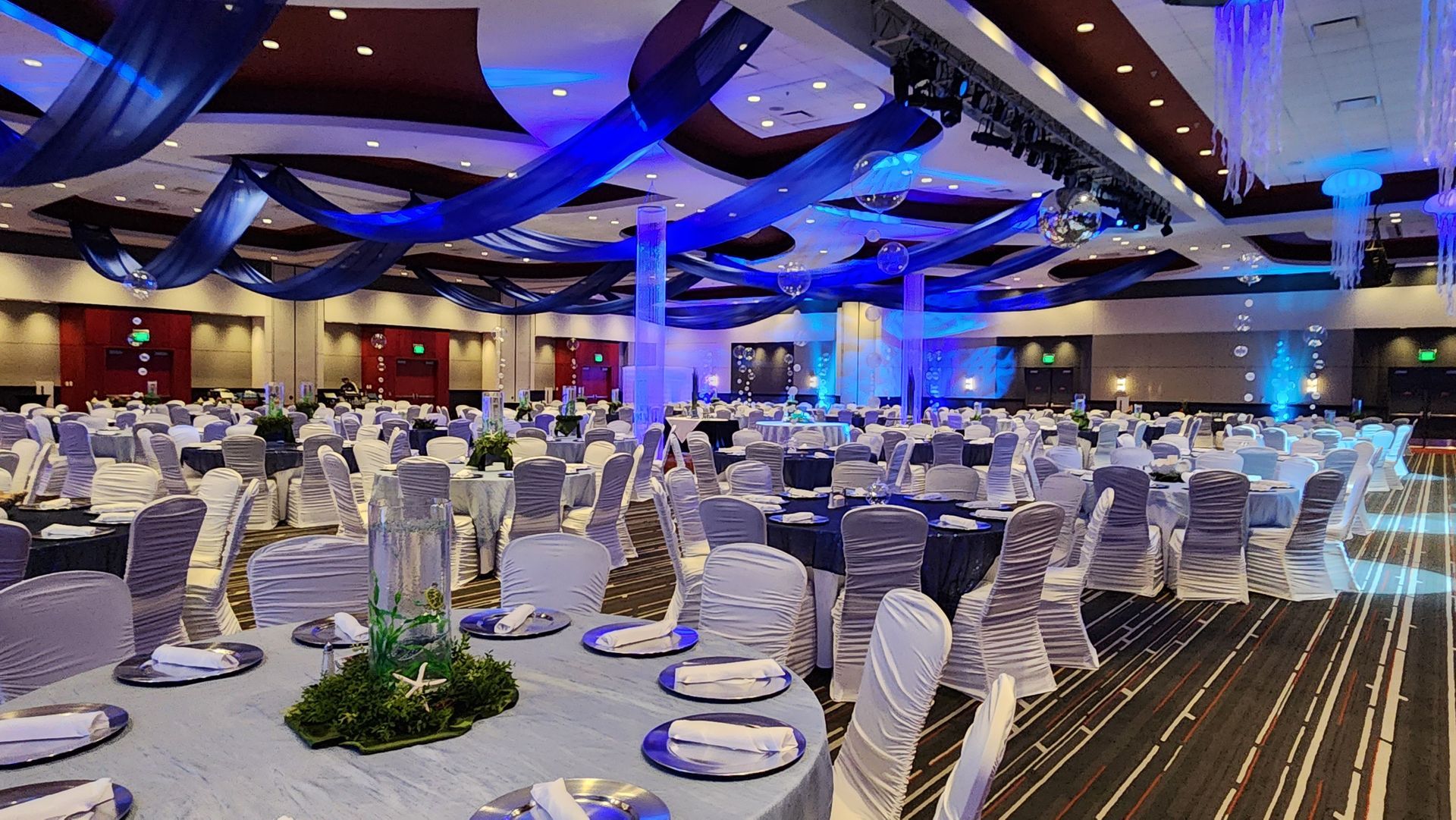 A large ballroom with tables and chairs set up for a wedding reception.