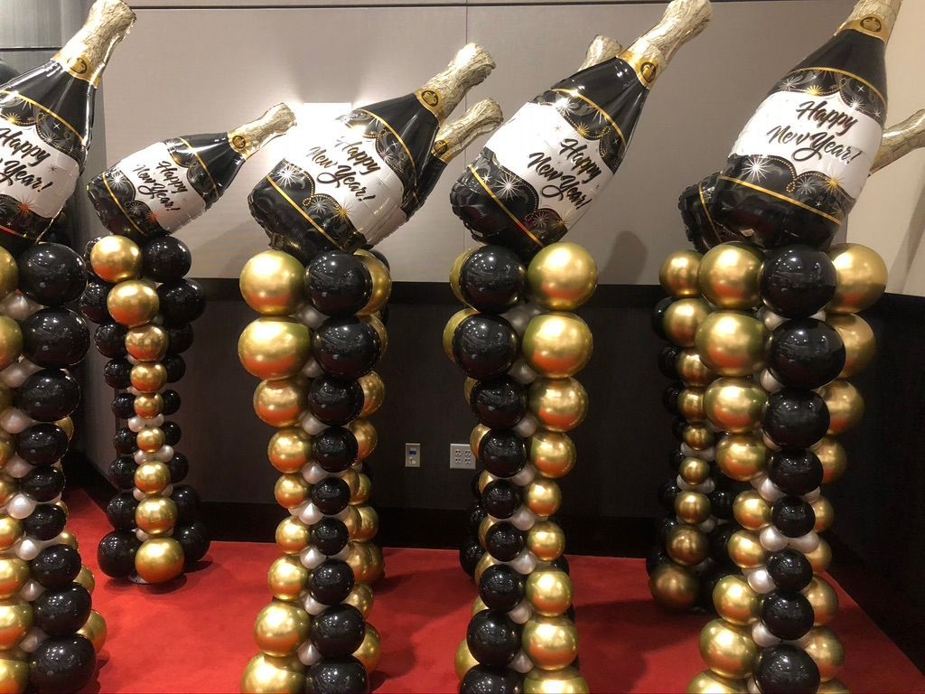 A row of balloons shaped like champagne bottles are sitting on top of each other on a red carpet.
