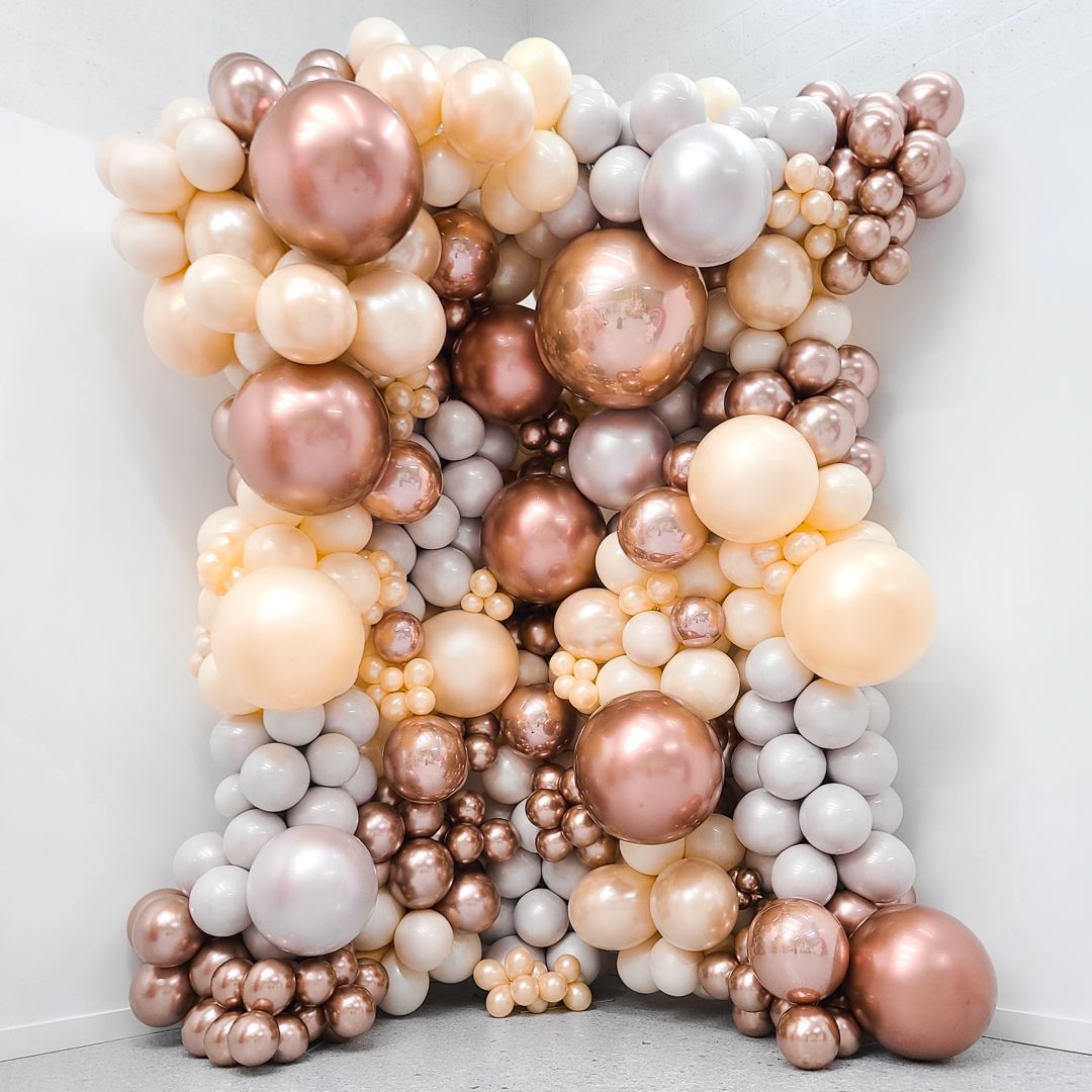 A bunch of balloons are stacked on top of each other on a wall.