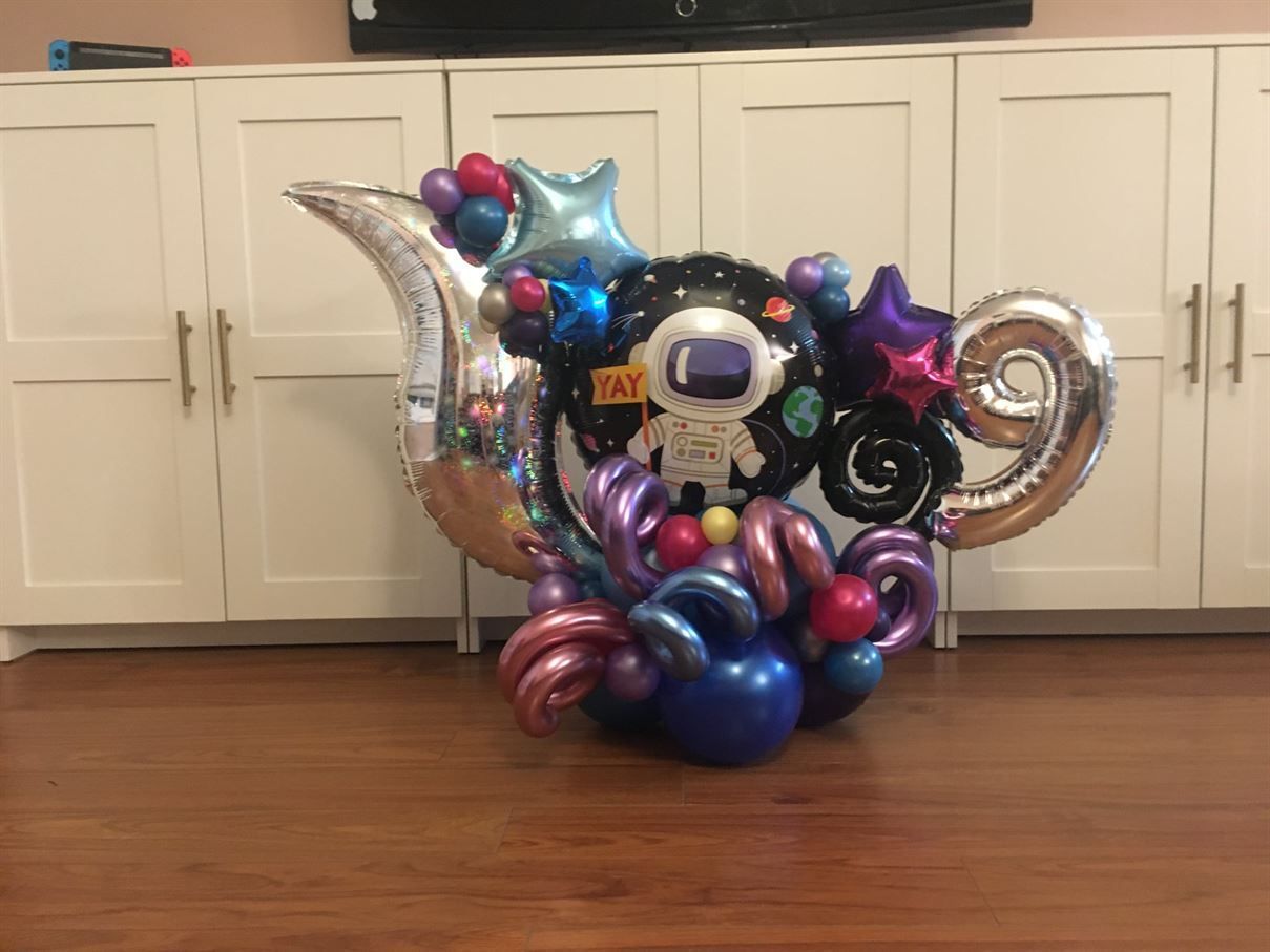 A bunch of balloons are sitting on a wooden floor in a room.