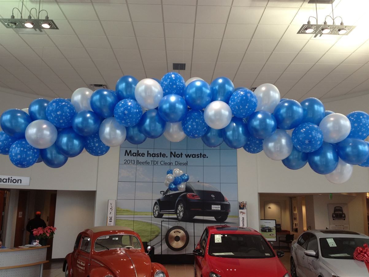 A car dealership is decorated with blue and white balloons