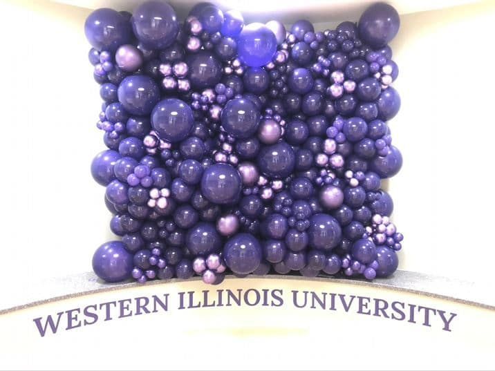A wall of purple balloons with a sign that says western illinois university