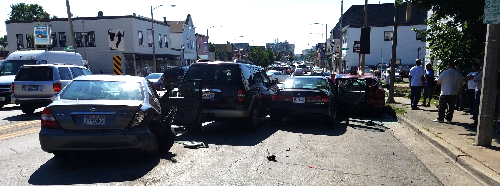 Cars involved in a traffic accident on a city street. People stand on the sidewalk.