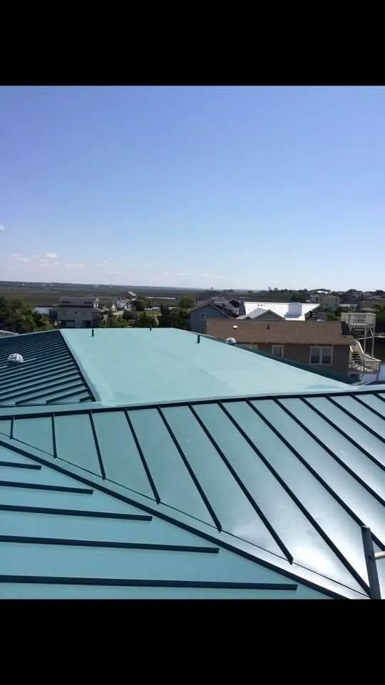 Blue metal roof overlooking a residential neighborhood under a clear sky