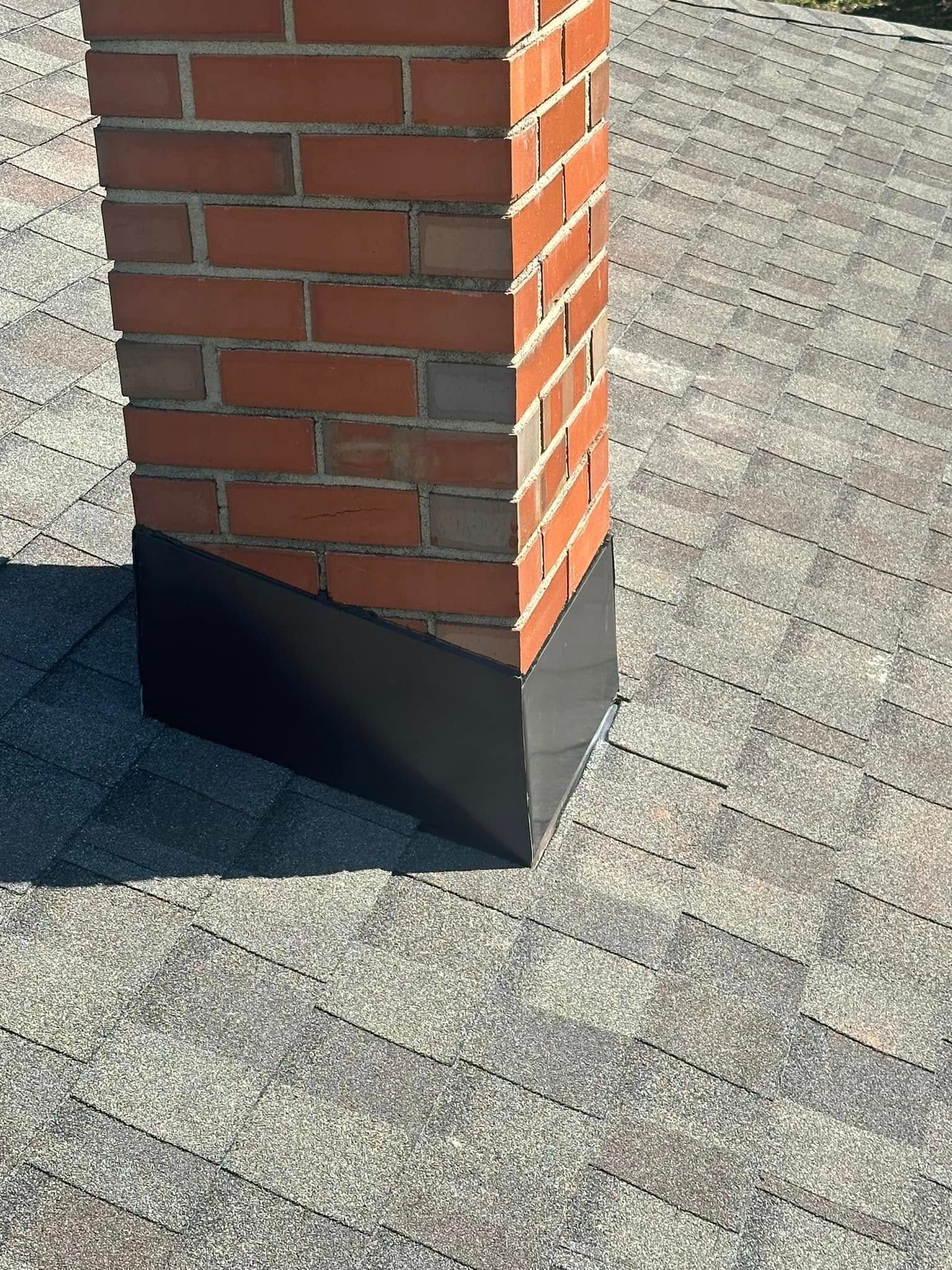 Brick column with a black metal base on a sunlit concrete surface.