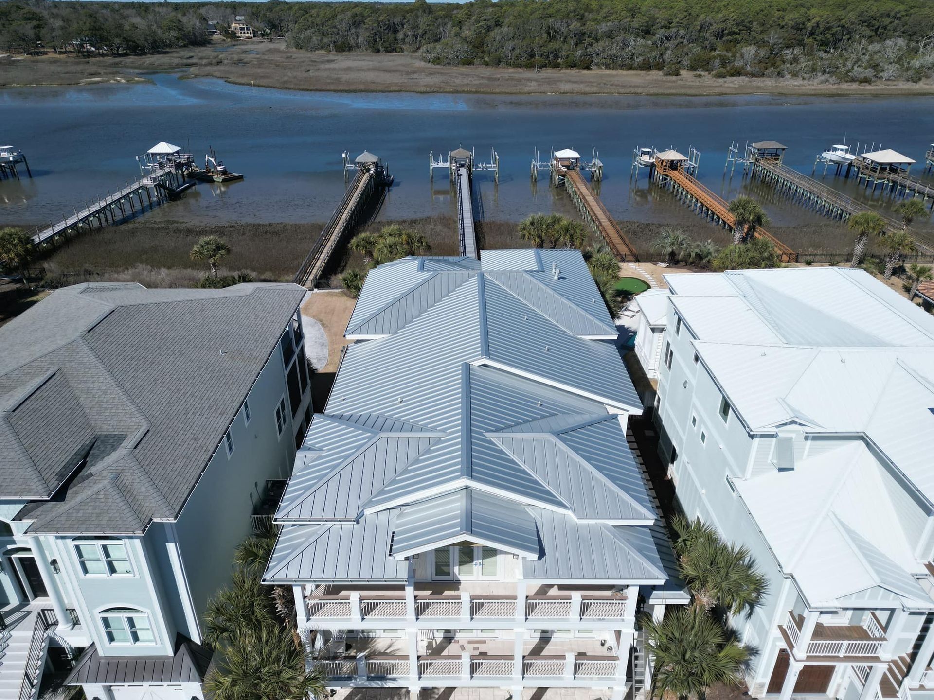 Aerial view of waterfront homes with docks, boats, and a river behind them