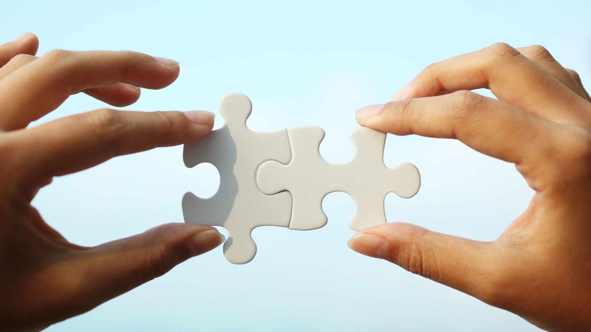A person is holding two puzzle pieces in their hands.