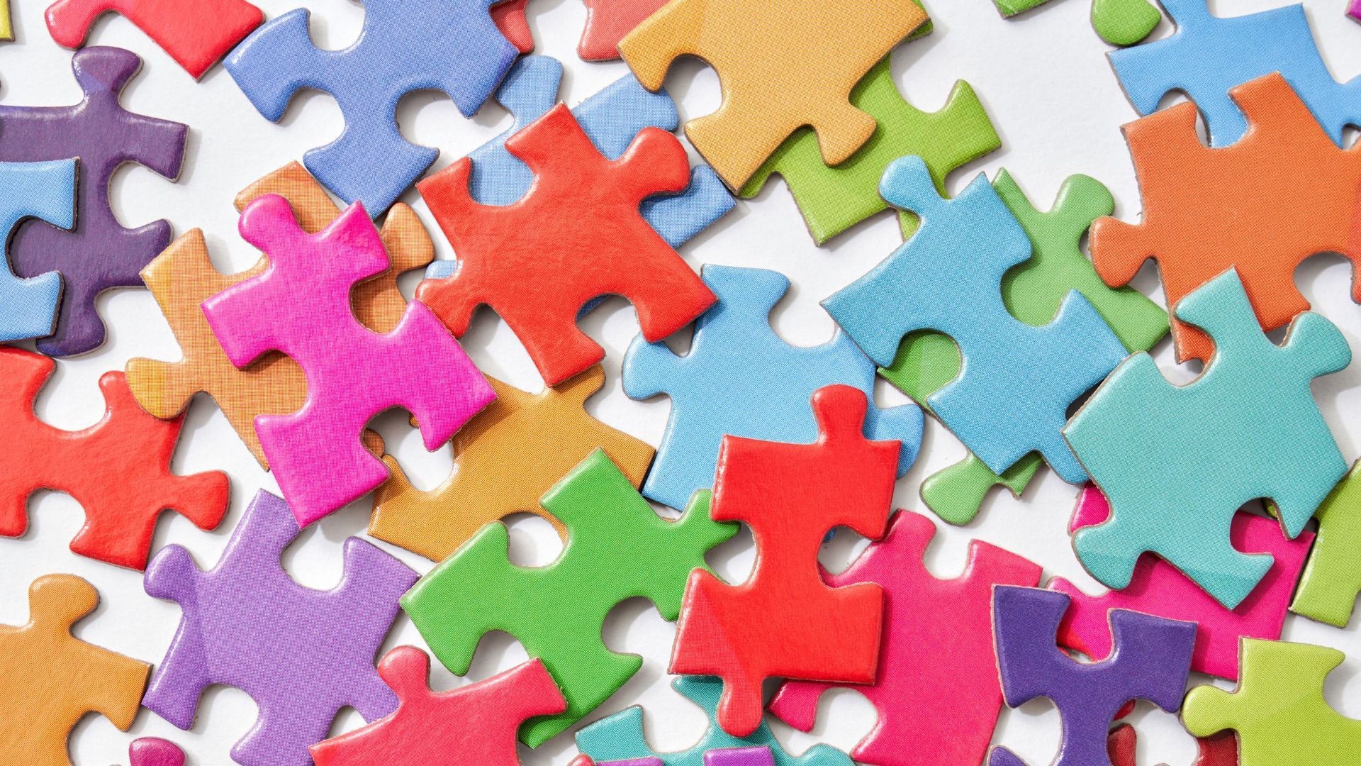 A pile of colorful puzzle pieces on a white surface.