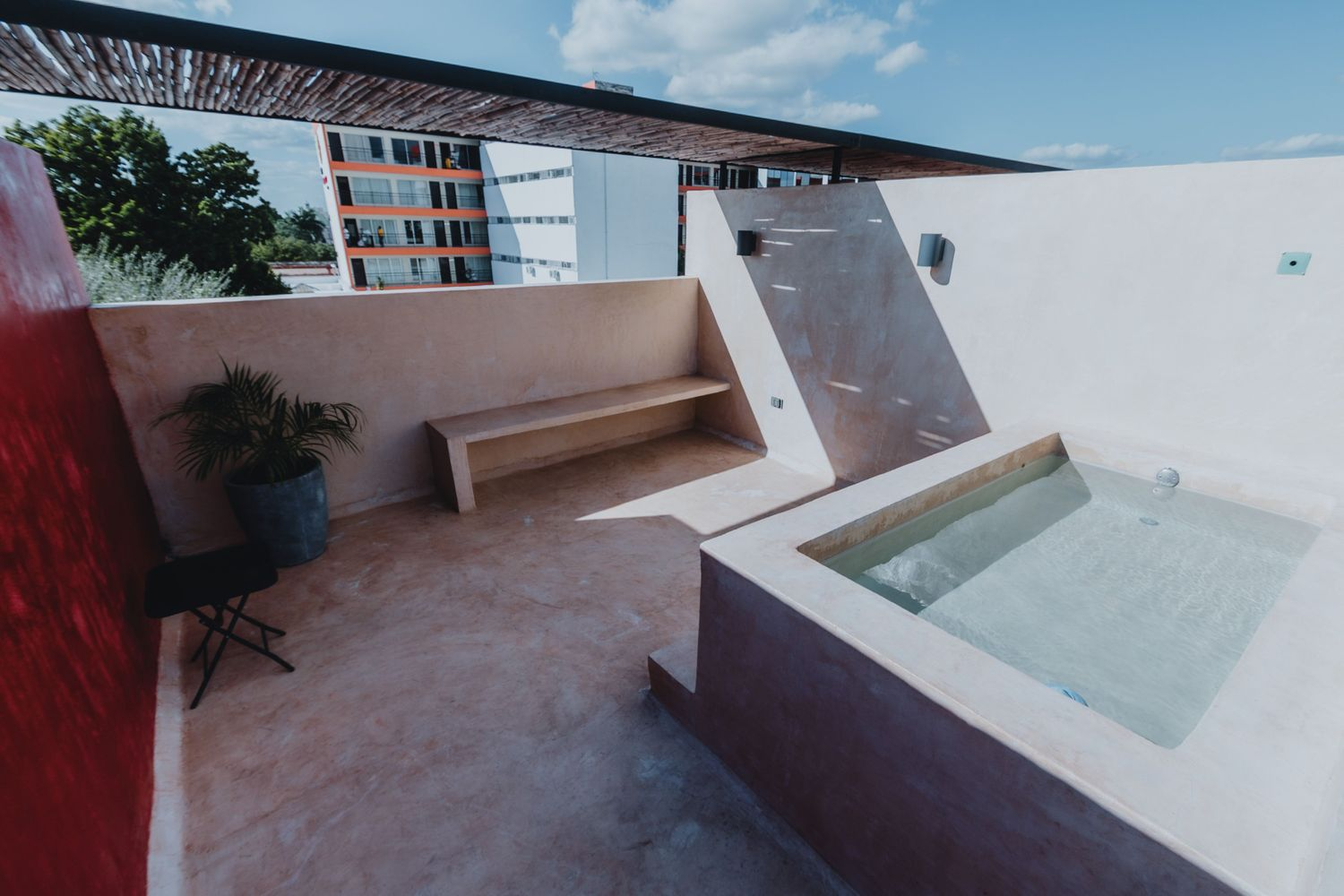 Modern rooftop patio with bench, planter, and a small square pool under a pergola