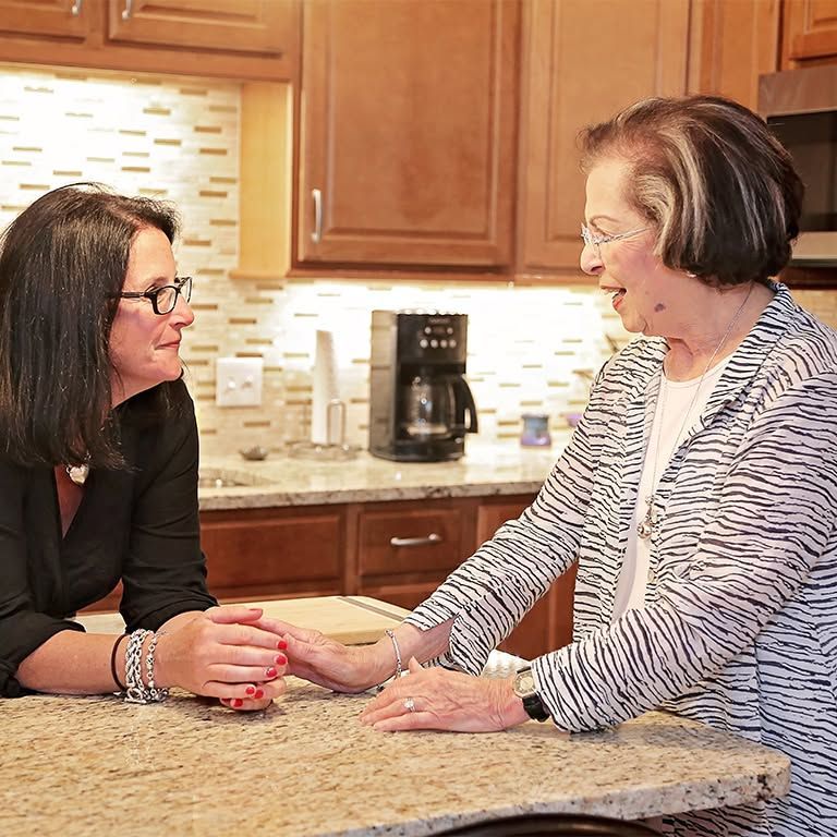 Two women talking and holding hands across a kitchen island
