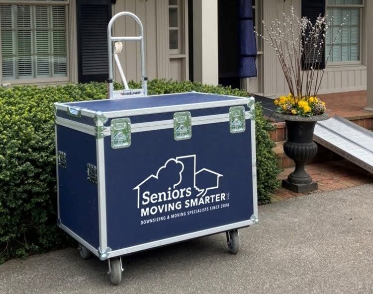 Blue rolling moving bin labeled “Seniors Moving Smarter” outside a house entrance