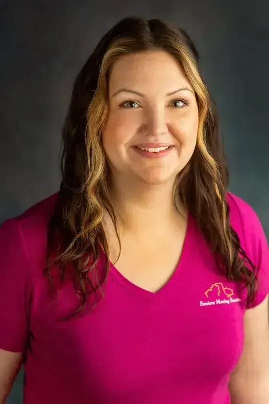 Smiling woman in a bright pink shirt against a dark studio background