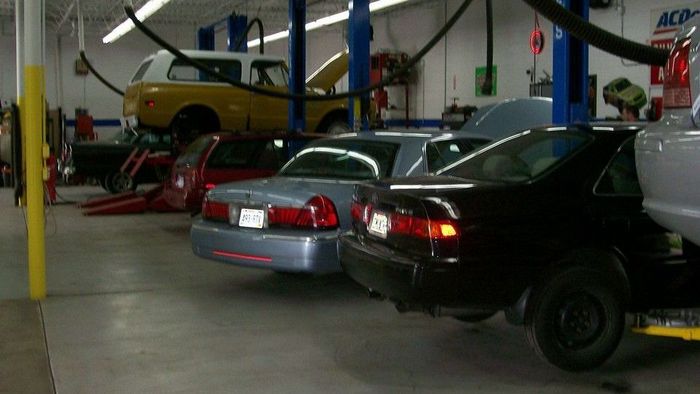 Cars in various states of repair in a busy auto shop, with vehicles on lifts and jacks. | Silver Spring Automotive