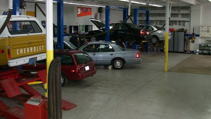 Auto repair shop with cars on lifts, a red and white pickup truck, and a red wagon.  | Silver Spring Automotive