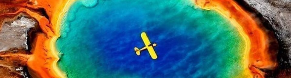 Yellow plane over vivid blue-green hot spring with orange-red mineral edges