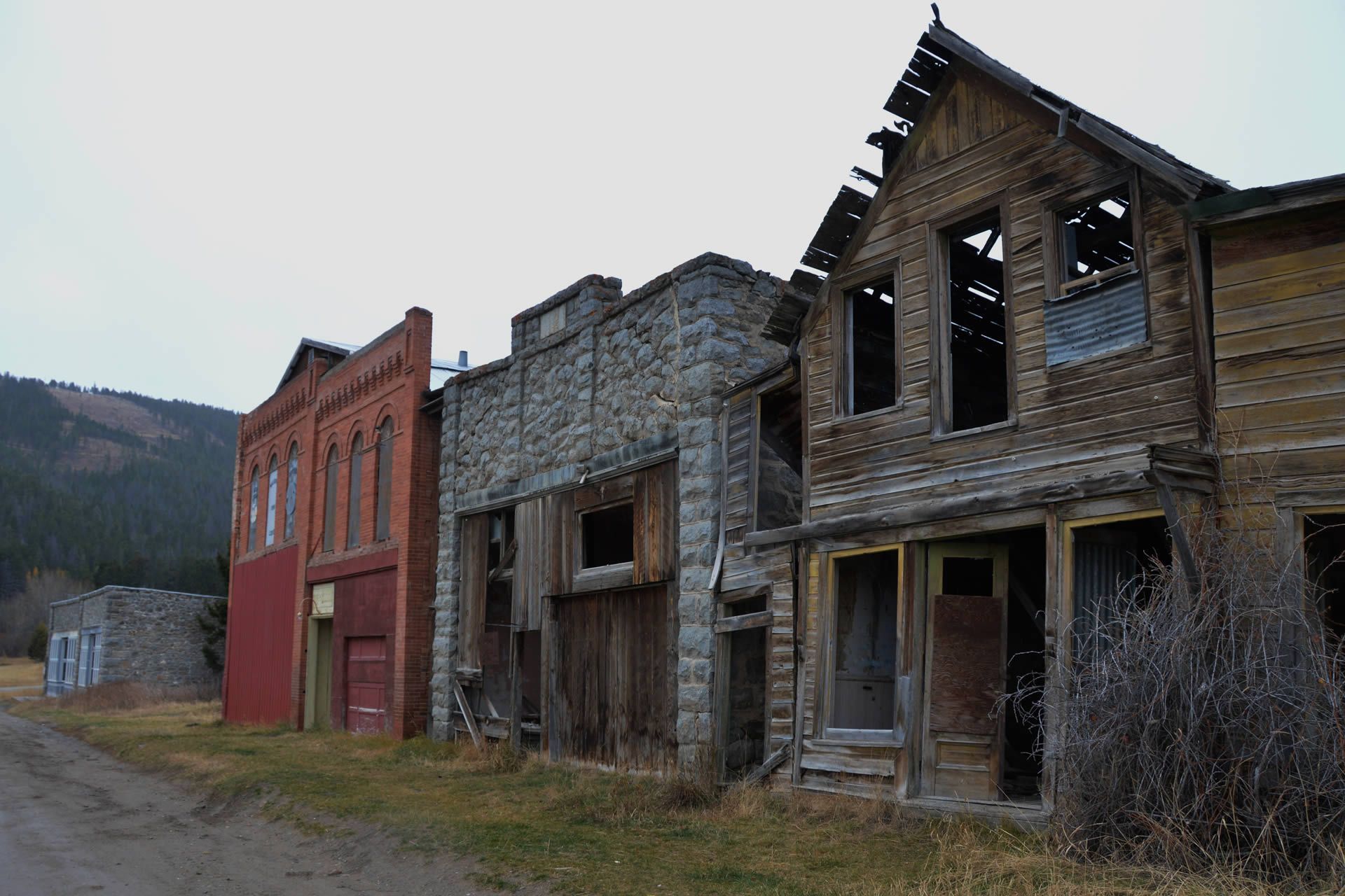 Abandoned old western-style storefronts in a quiet small town, with weathered wood and brick buildings.