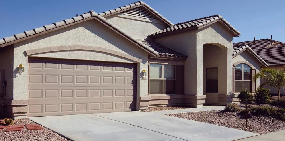 Suburban single-story house with beige stucco, two-car garage, and front walkway