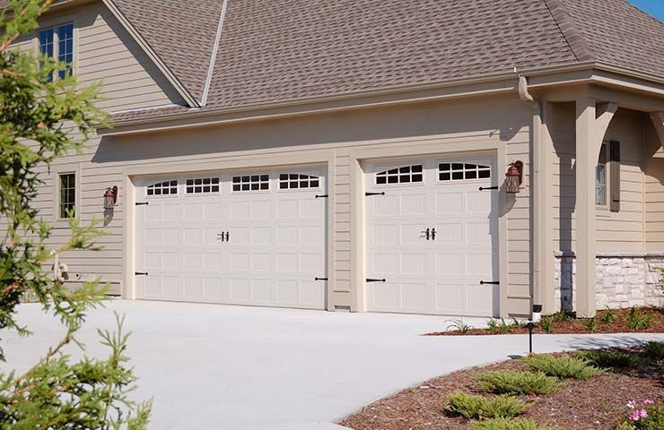 Suburban house exterior with two white garage doors and a light concrete driveway