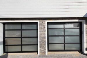 Two black garage doors with frosted glass panels on a stone-and-white exterior wall