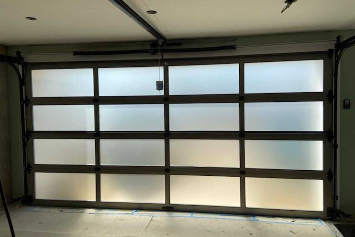 Closed frosted glass garage door with dark horizontal framing in a garage interior