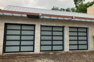 Modern brick building with three large frosted glass garage-style doors and a slanted metal roof
