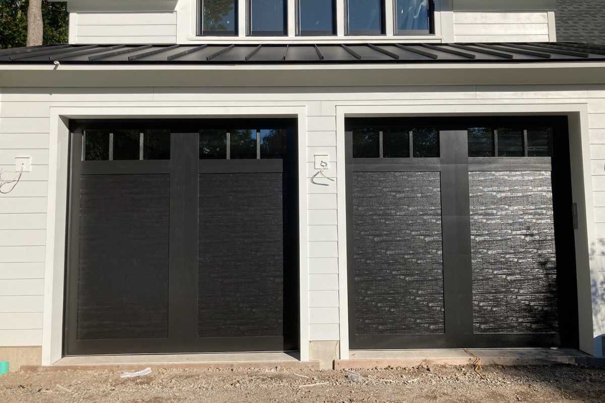 Two black garage doors on a light-colored house exterior
