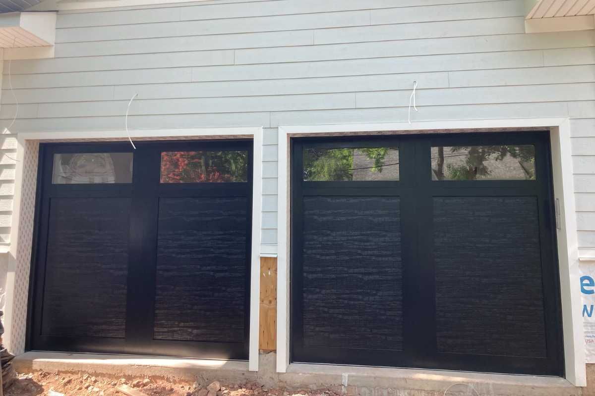 Two black-covered windows on a light gray house exterior under construction