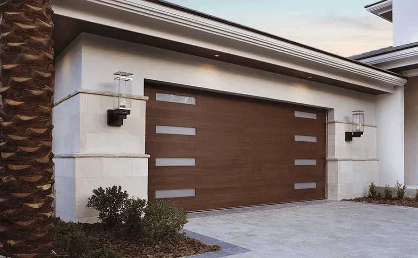 Modern house garage with a brown paneled door, white stucco walls, and wall lanterns